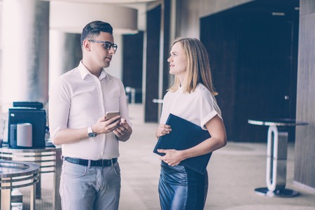 Serious executive and female secretary talking in business cafeteria. Young Caucasian businesswoman...