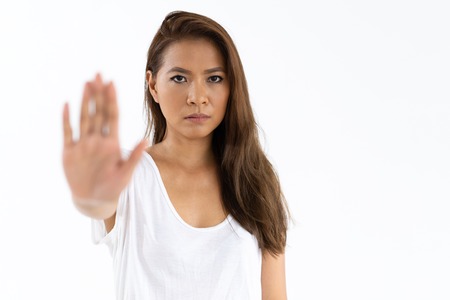 Strict girl showing stop sign. Serious young woman raising hand with open palm in warning gesture. Warning conceptの写真素材
