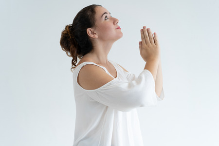 Positive lovely woman holding hands together and praying. Young lady begging for something. Prayer...