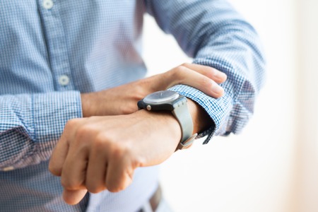 Closeup of business man checking time on wristwatch. Entrepreneur waiting for someone. Time management concept. Cropped view.