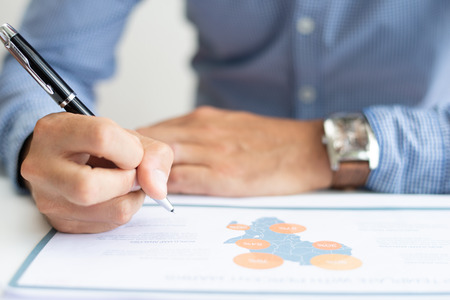 Closeup of business man studying map chart. Person working at desk. Analysis concept. Cropped front view.の写真素材