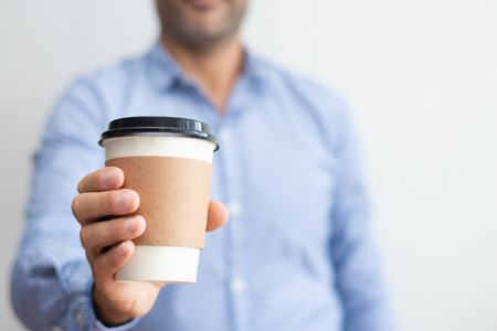 Closeup of man holding disposable cup. Person standing and having break. Coffee break concept. Closeup front view.の写真素材