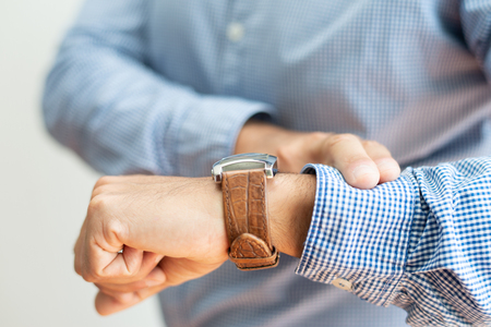 Closeup of business man checking time on watch. Entrepreneur waiting for someone. Appointment concept. Cropped front view.の写真素材