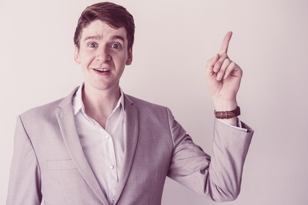 Confident inquisitive male teacher in gray jacket showing index finger. Content enterprising young...