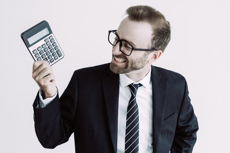 Smiling business man holding, showing calculator display and looking at it. Calculation concept. Isolated front view on white background.の写真素材