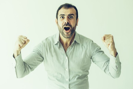 Ecstatic emotional male fan cheering for favorite sport team. Excited handsome Hispanic man with beard screaming and looking at camera. Expression conceptの写真素材