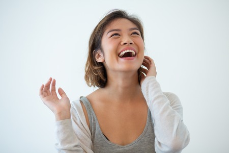 Portrait of happy young woman laughing cheerfully. Excited Asian woman looking up and touching face. Joy and positivity conceptの写真素材