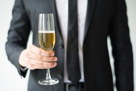 Closeup of business man holding goblet with champagne. Person celebrating event. Holiday concept. Isolated cropped front view on white background.の写真素材