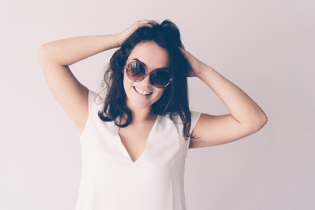 Careless beautiful young woman touching hair and looking at camera. Lady wearing summer clothes. Summer vacation concept. Isolated front view on white background.の写真素材