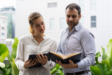 Serious boss and his assistant checking schedule. Two business employees looking at notes during...