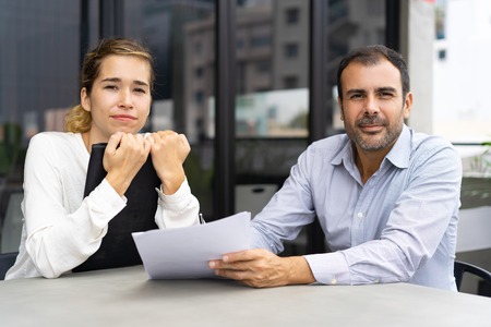 Group of experts discussing papers. Business man and woman posing at camera while working on...