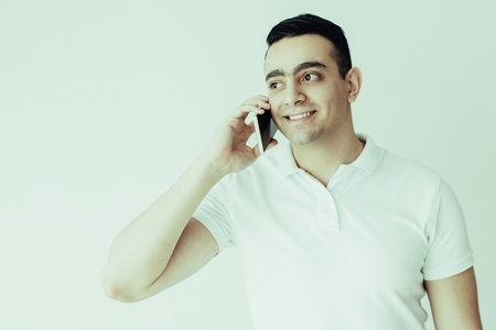 Smiling handsome man talking on smartphone. Young man calling on mobile phone. Communication concept. Isolated front view on white background.の写真素材