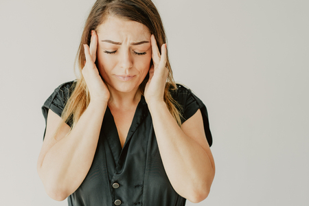 Tired stressed young woman in black dress feeling headache and massaging temples. Sad annoyed woman...