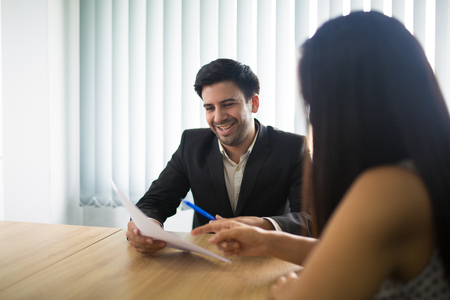Happy young businessman discussing contract at meeting with female partner. Caucasian businessman and businesswoman talking about project or report. Meeting and teamwork conceptの写真素材