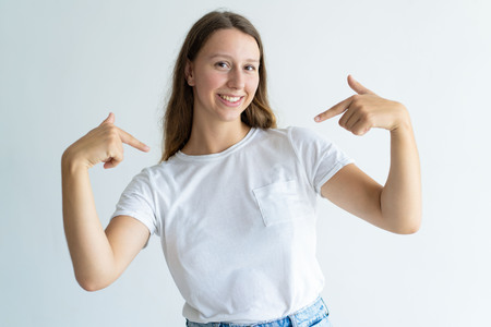 Smiling lovely young woman pointing at herself. Pretty lady looking at camera. Self-reliance concept. Isolated front view on white background.の写真素材