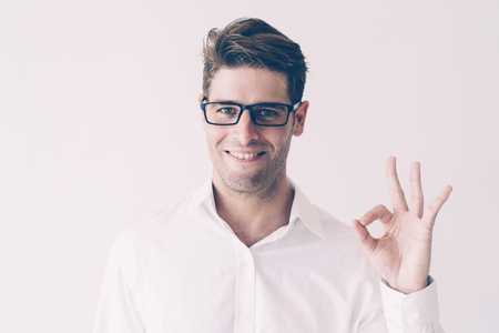 Portrait of successful young businessman showing ok sign. Caucasian student in glasses showing alright gesture. Success conceptの写真素材