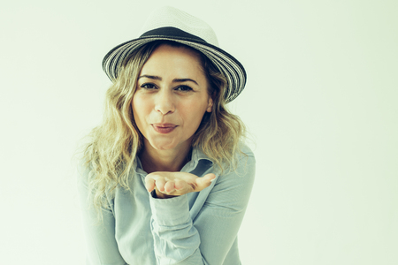 Content pretty woman simulating kiss and puckering lips. Cheerful carefree lady in sun hat blowing air kiss while enjoying vacation. Expressing feelings conceptの写真素材