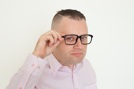 Serious suspicious office employee touching temple of eyeglasses. Closeup of young Caucasian man adjusting glasses and looking at camera. Glasses wearing conceptの写真素材