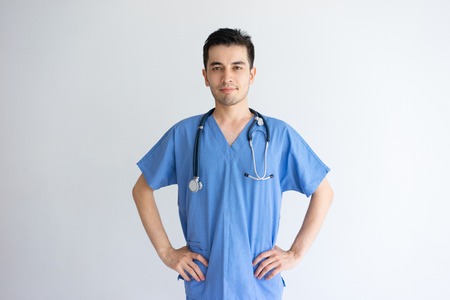 Content handsome young male physician posing at camera. Handsome guy standing and wearing blue medical uniform. Medicine concept. Isolated front view on white background.の写真素材
