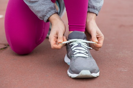 Close-up of runner tying lace of sport shoe while preparing for race. Unrecognizable woman tying bow on jogging shoe. Sport shoe conceptの写真素材