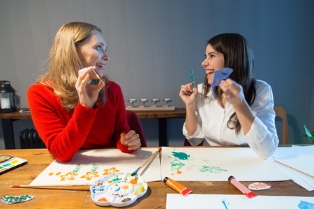 Amazed art school students working with stencils. Two girls enjoying painting class. Enjoying art...