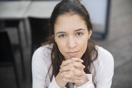 Close-up of young confident woman looking at camera. Portrait of Latin American girl posing in cafe. Young woman conceptの写真素材