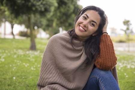 Happy calm pretty girl tidying up hair and smiling at camera. Outdoor portrait of young woman in...