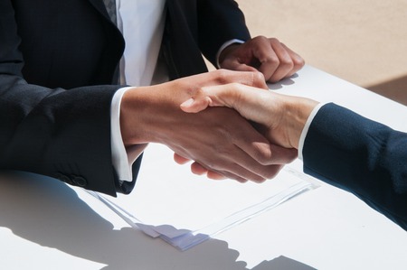 Closeup of business people shaking hands outdoors. Business man and woman wearing formal clothes and...