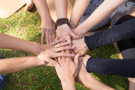 Top view of stack of hands against green grass. Friendship, teamwork or community gesture. Unity or...