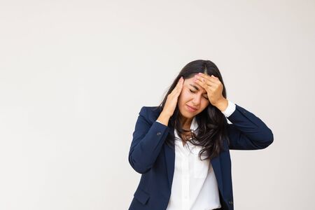 Tired young businesswoman having headache. Stressed young woman in formal wear suffering from headache isolated on grey background. Emotion conceptの写真素材