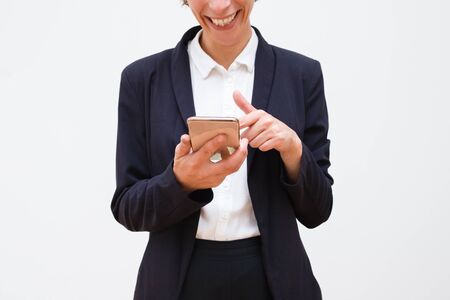 Cropped shot of woman using smartphone. Cheerful businesswoman in formal wear using mobile phone isolated on grey background. Technology conceptの写真素材