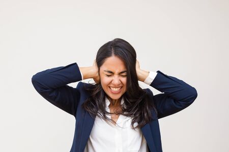 Young businesswoman closing ears. Stressed young woman in formal wear standing with closed eyes and closing ears isolated on grey background. Emotion conceptの写真素材