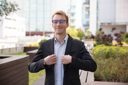 Happy confident businessman standing for camera in business district and smiling. Portrait of...