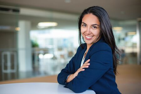 Cheerful young businesswoman. Beautiful happy young woman in formal wear sitting at table and smiling at camera. Emotion conceptの写真素材
