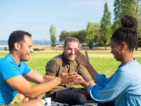 Cheerful friends playing at picnic. Happy young friends gathering together and spending time in...