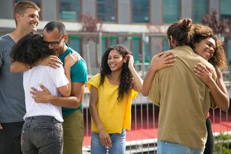 Multiethnic team of friends meeting and hugging outside. Latin, black, Caucasian men and women...
