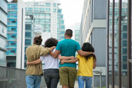 Close male and female friends walking down city street together. Rear view of mix raced people walking outside and hugging each other. Friendship and support conceptの写真素材