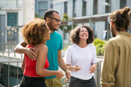 Mix raced group of people having fun and spending great time outdoors. Close interracial friends meeting on outdoor building terrace, hugging, chatting and laughing. Friendship and leisure conceptの写真素材