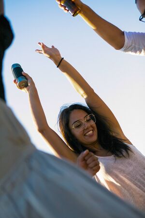 Tilted view of smiling people having fun together during party. Young friends dancing with beer...