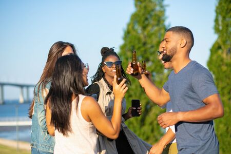 Smiling young people relaxing at open air party. Happy friends dancing and drinking beer during sunset. Leisure conceptの写真素材