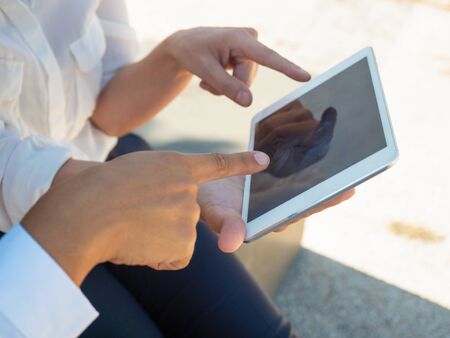 Businesswomen using online app on tablet together. Closeup of tablet in female hands and fingers...