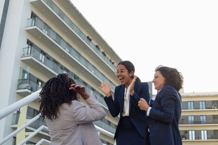 Excited young businesswomen outdoor. Happy multiethnic female colleagues triumphing together on street. Success conceptの写真素材