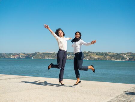 Excited happy female business colleagues having fun outside. Businesswomen in office clothes and...
