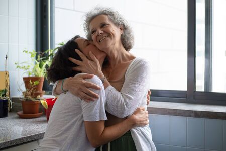 Happy daughter kissing senior mother. Cheerful middle aged daughter kissing and hugging happy senior...