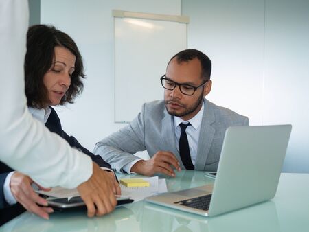 Female mentor training young male intern. Business man and woman sitting at meeting table, studying...