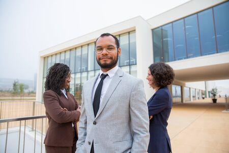 Cheerful professional business people. Multiethnic business team standing together, smiling at camera and looking at each other. Cooperation conceptの写真素材