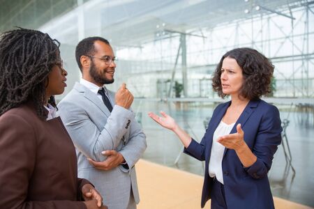Serious and smiling business colleagues. Professional male and female multiethnic business people standing together and talking. Cooperation conceptの写真素材