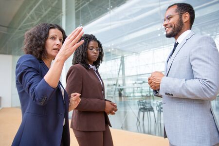 Multiethnic businesswomen talking with smiling businessman. Professional male and female business...