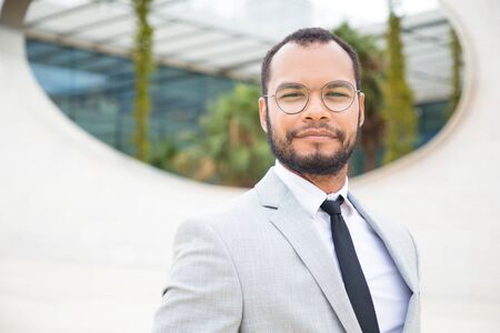 Positive confident businessman posing outside. Handsome business man in eyeglasses and office suit...