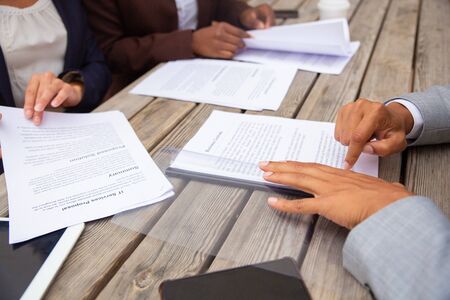 Business people studying contract terms at meeting. Business man and women sitting at cafe table and reading documents. Paperwork closeup conceptの写真素材